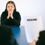 A woman in a job interview facing two employers with a focus on her resume.