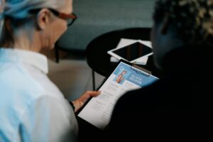 Business professionals conducting an interview with resume on clipboard in an office setting.