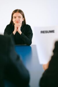 Woman in a serious job interview with resume in focus, sitting at a table.